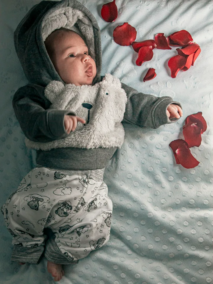 A newborn in white lying on a patterned blanket