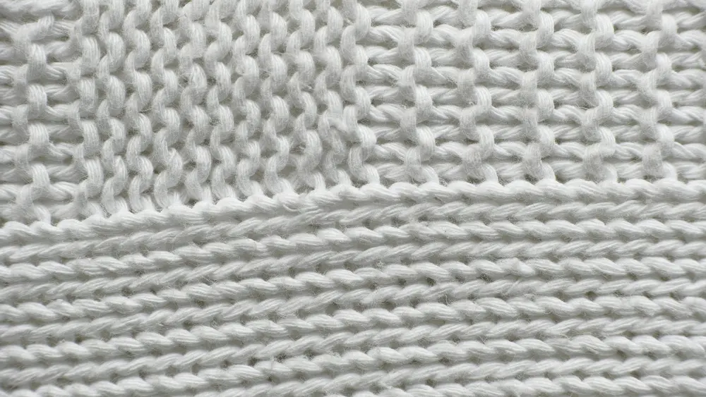 A close-up of white cotton knit, the stitch loops clearly visible