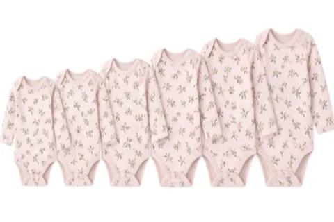 Six pink floral bodysuits in ascending sizes, laid in a row from smallest to largest
