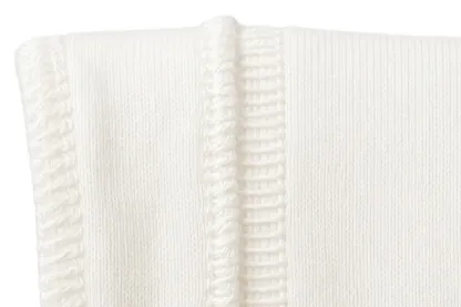 Two seam finishes side by side on white knit, an overlocked edge beside a flatlocked one