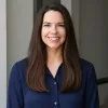 Faith H Gilmer, in a navy shirt against a plain grey wall