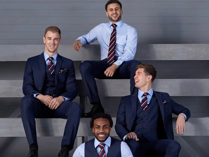 Four team members in navy suits on concrete steps — company workwear