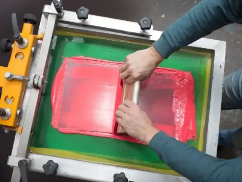 A squeegee pulling ink across a screen — custom screen printing