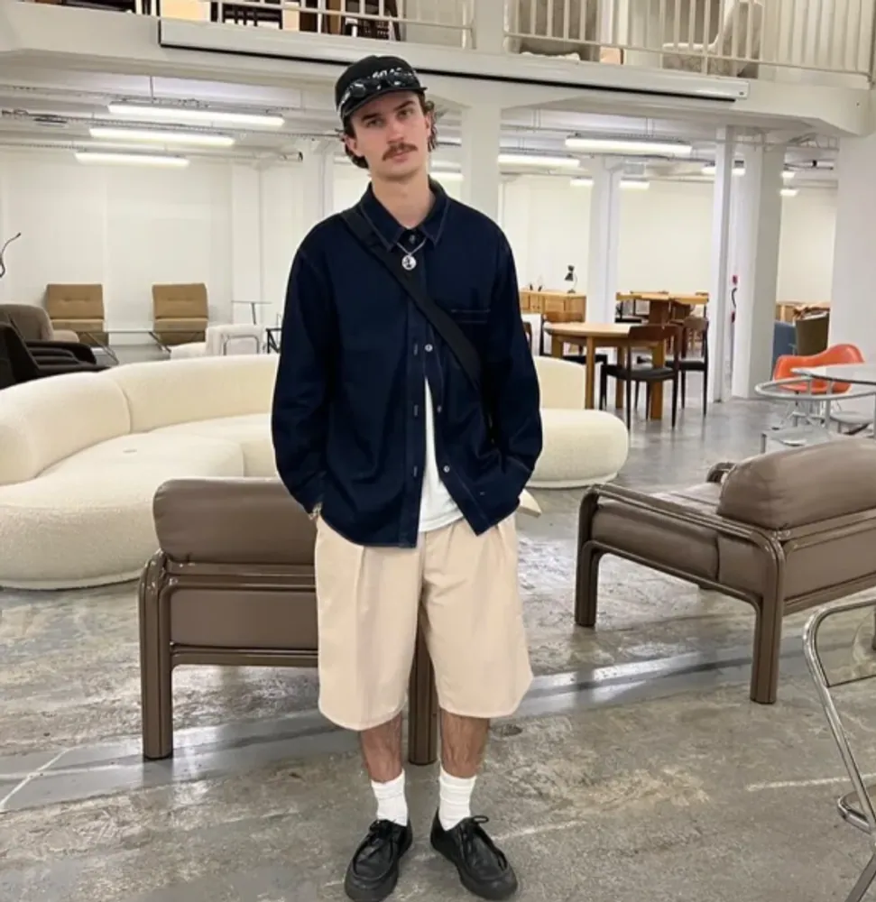 A client in a navy overshirt and khaki shorts in a loft studio