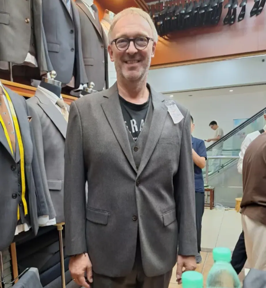 A client trying on a grey suit jacket in the showroom