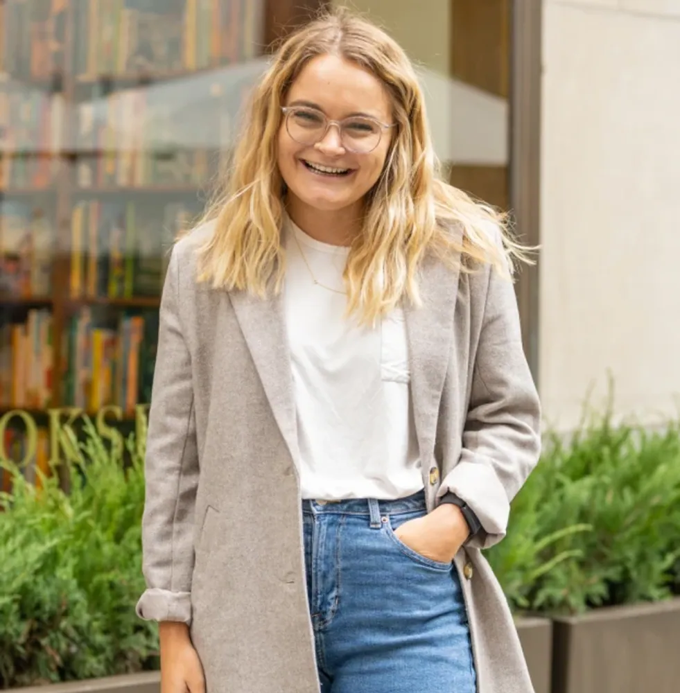 A client in a stone coat, white tee and jeans on the sidewalk