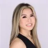 Michelle Tran, in a black top against a plain pale wall