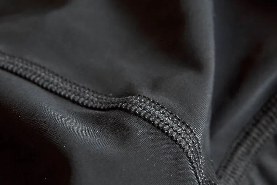 Dense black knit filling the frame, a flatlock seam running diagonally across the middle