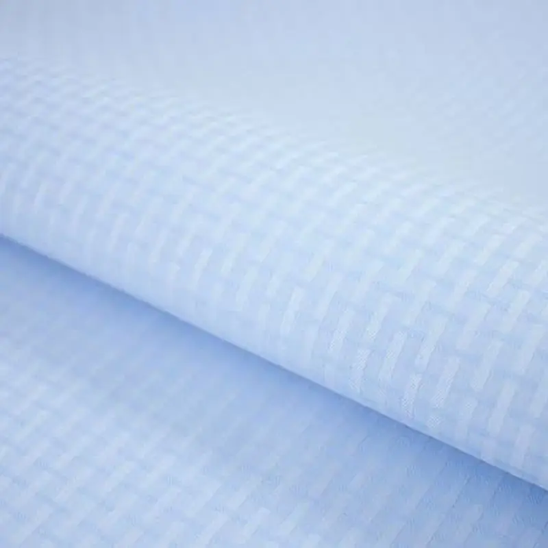 Check-woven pale blue cloth draped over a soft edge, the weave reading as a fine grid