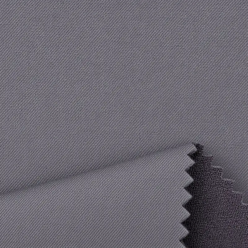 Bonded softshell in grey filling the frame, a zigzag cut edge lifting to show the darker backer behind it