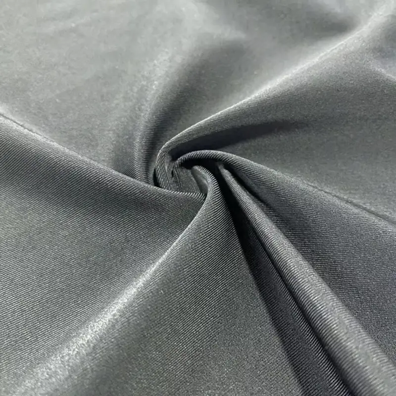 Recycled polyester in grey-green twisted into a spiral at the centre, a bright sheen catching across the folds
