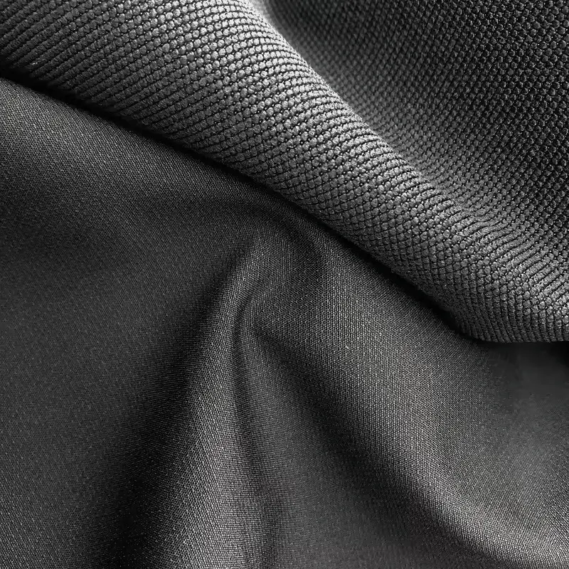 Stretch woven in mid grey folded across the frame, a fine diagonal rib above a smoother matte face