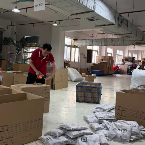 Packing a carton, a worker in a red polo surrounded by stacked boxes and grey polybags.