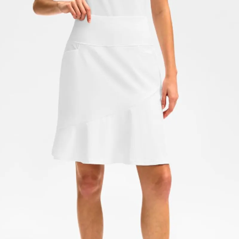 Flared white skort worn over bare legs, a hand resting on the waistband above a soft ruffle at the hem
