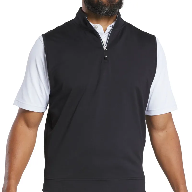 Black sleeveless zip-neck vest worn over a white polo, photographed from the chest down to the hem
