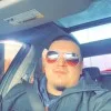 Mark Torres, in sunglasses and a blue jacket, sitting in the driver’s seat of a car
