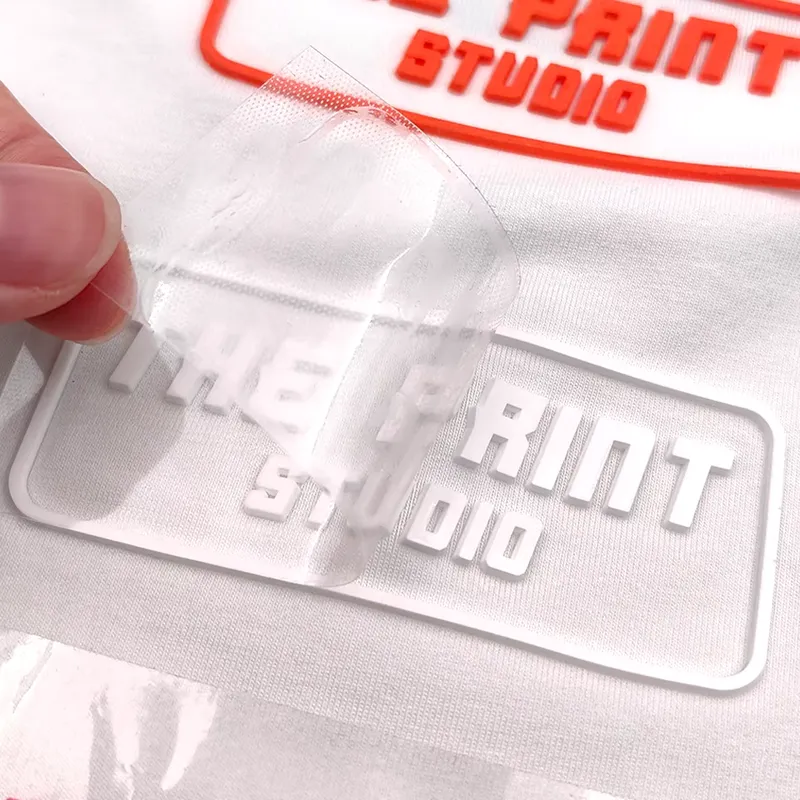 Silicone wordmark with the transfer film peeled back, the raised lettering left on white fabric
