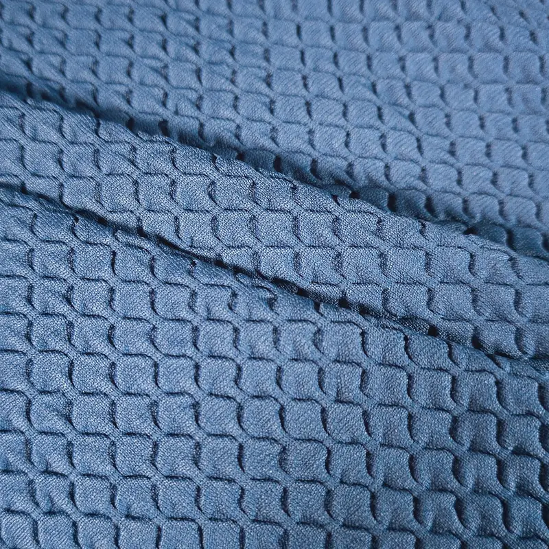 Raised in a grid across a blue engineered knit, the waffle cells and their creases reading as texture