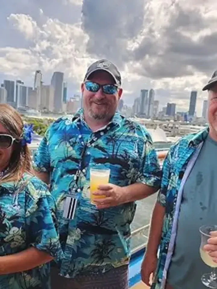 Two customers in matching teal floral shirts at a rooftop by the city skyline