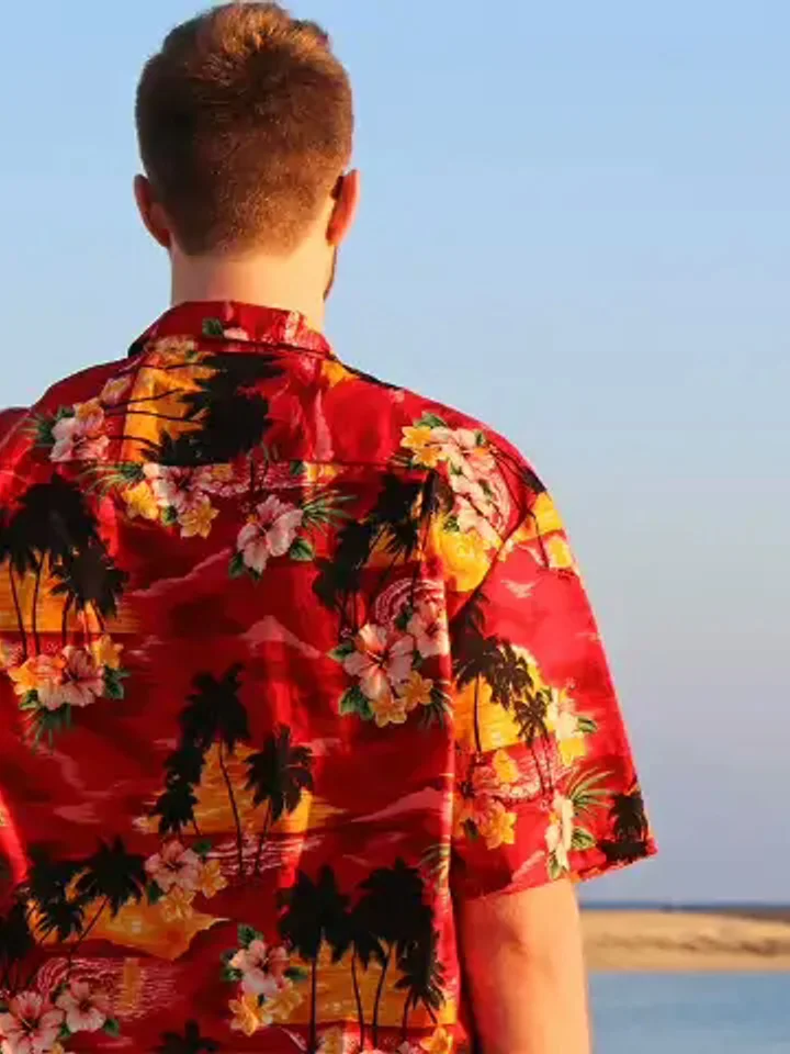 A customer wearing a red floral Hawaiian shirt on the beach
