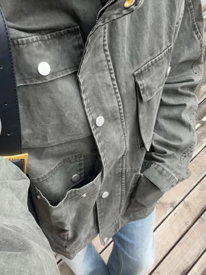 Close-up of a customer’s washed grey denim jacket, showing silver snap buttons and flap chest pockets