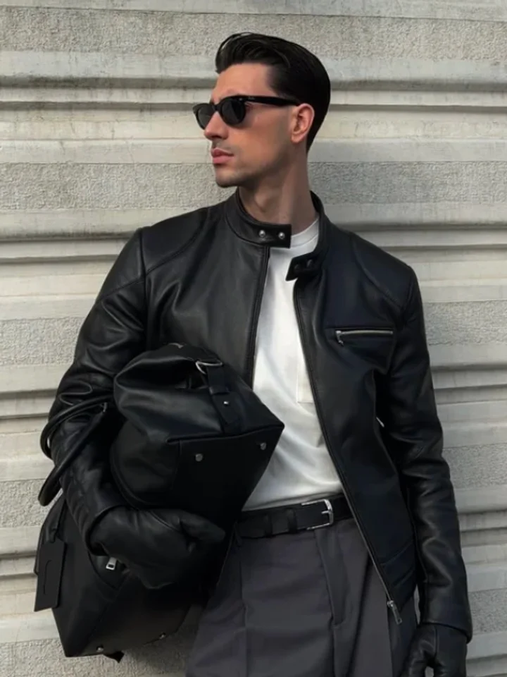 Black leather jacket and sunglasses, worn against a stone wall by a customer carrying a leather bag