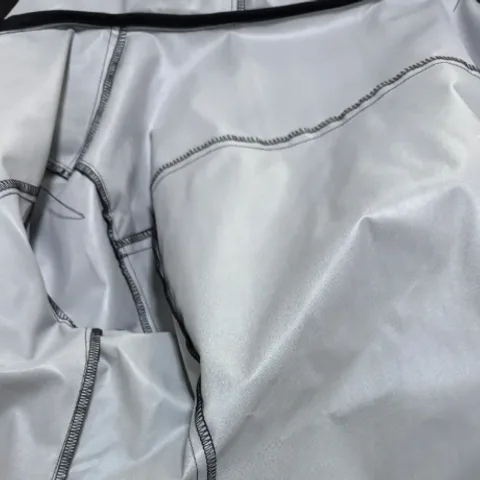 The inside of an unfilled jacket shell: silver-grey fabric with black overlocked seams against a contrast top trim