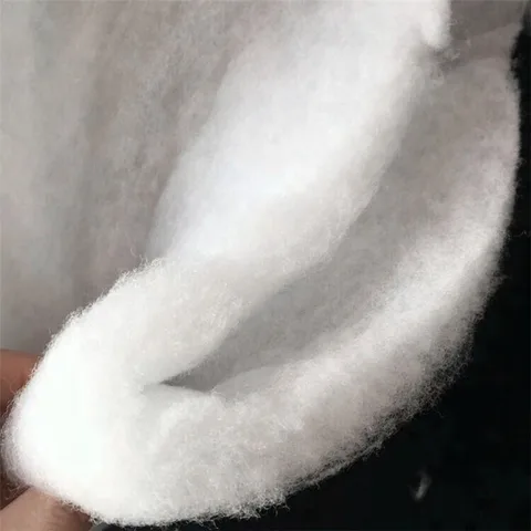 White cotton wadding batting held up to show the loft of the needled fibre