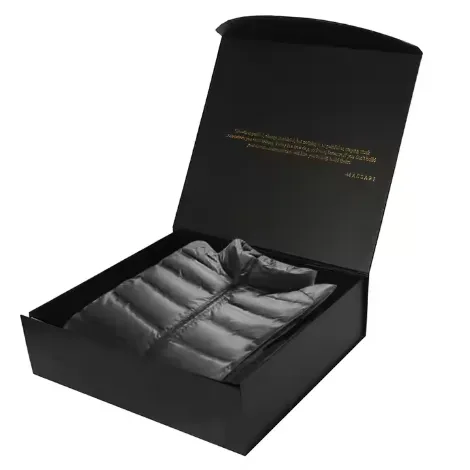 Black rigid gift box holding a folded grey quilted puffer jacket, with printed gold branding inside the lid