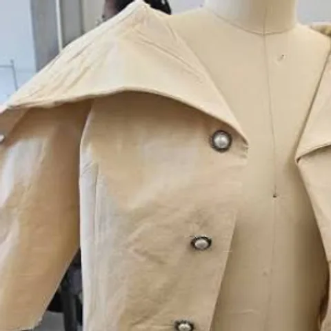 Calico toile jacket pinned on a dress form in the sample workshop
