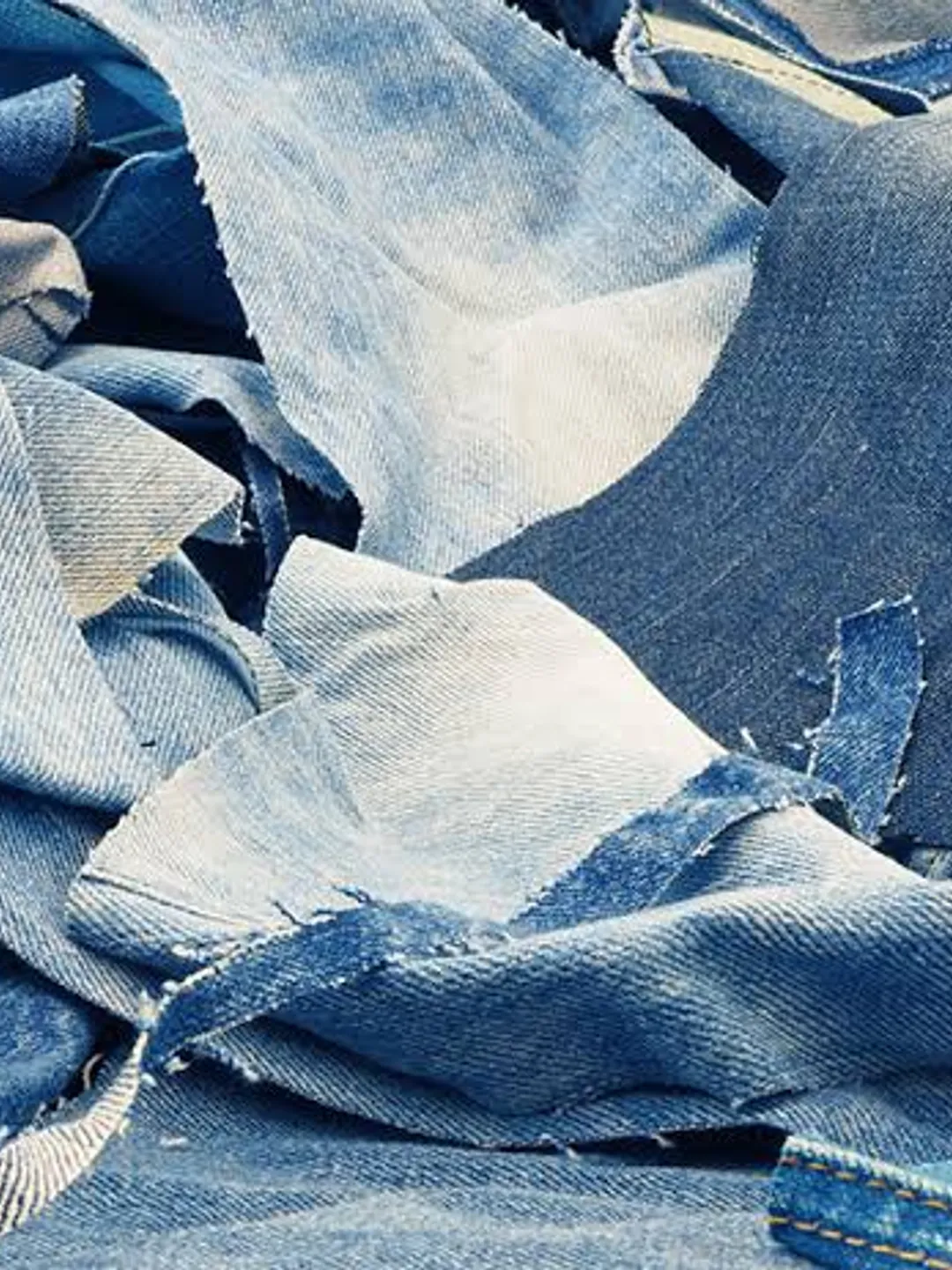 Pile of mixed recycled denim offcuts in indigo and grey