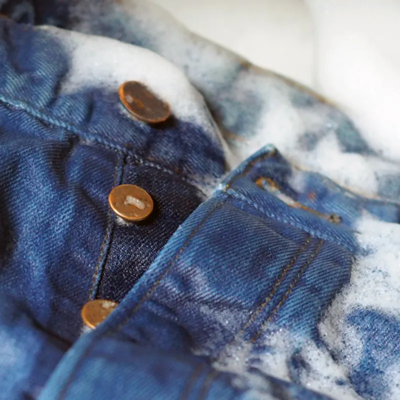 Close-up of enzyme-washed indigo denim with copper rivets