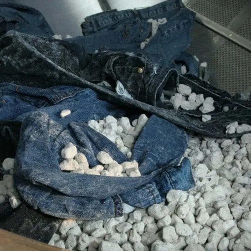 Jeans and pumice stones tumbling in a washing drum during stone washing