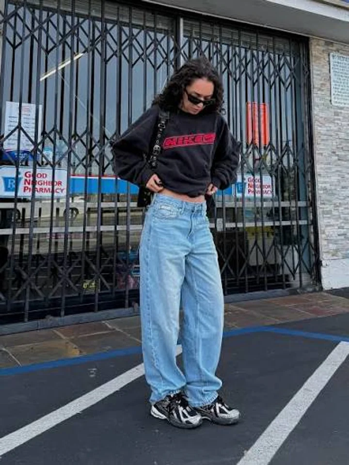 A customer in light-blue baggy jeans and a black sweatshirt in a parking lot