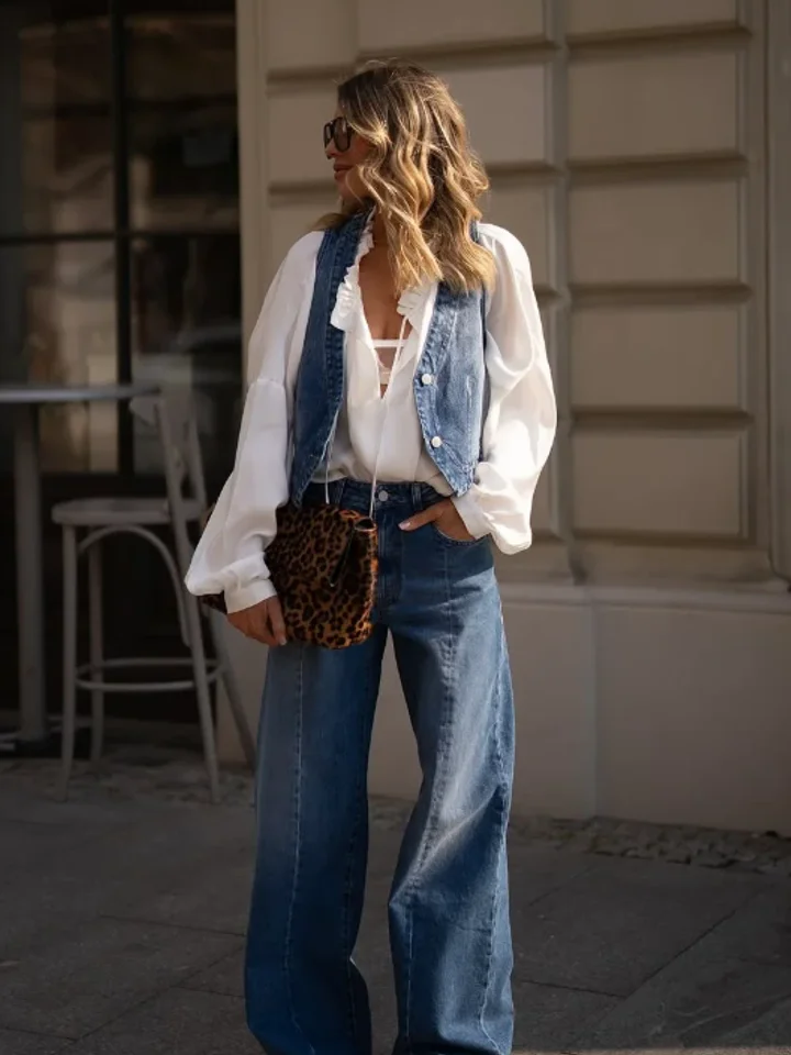 A customer in medium-blue wide-leg jeans with a denim vest over a white blouse