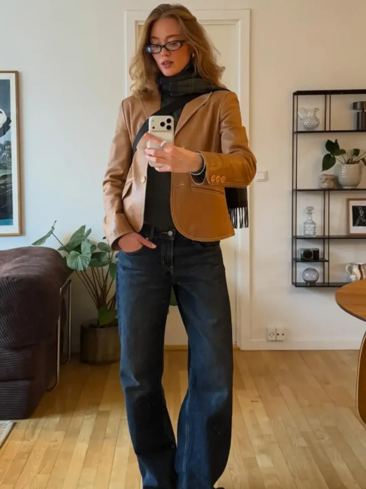 A customer in dark indigo straight-leg jeans with a tan leather blazer