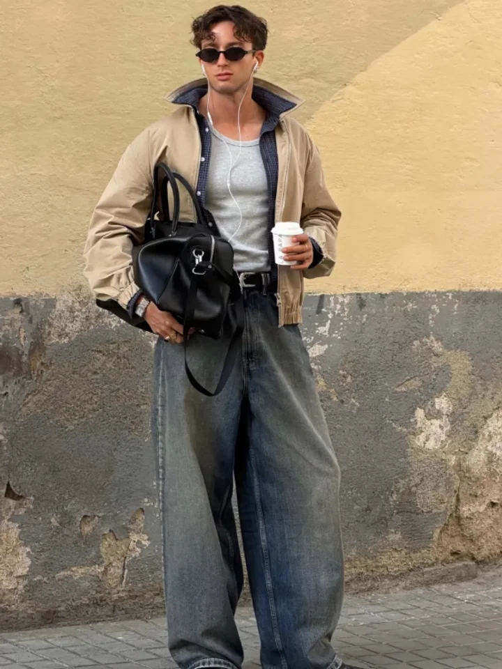 A customer in washed-grey baggy jeans and a tan jacket holding a coffee