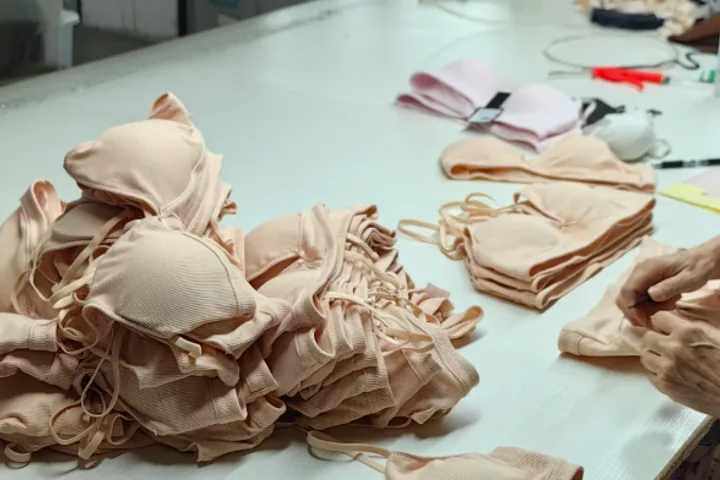 Finished bras and loose elastics piled on a table beside a stack of cut pieces