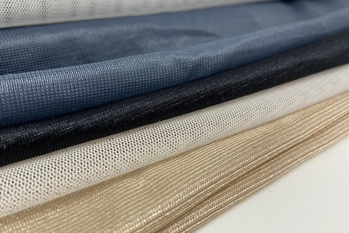 Folded lengths of navy, black, ivory and gold mesh stacked one behind the other