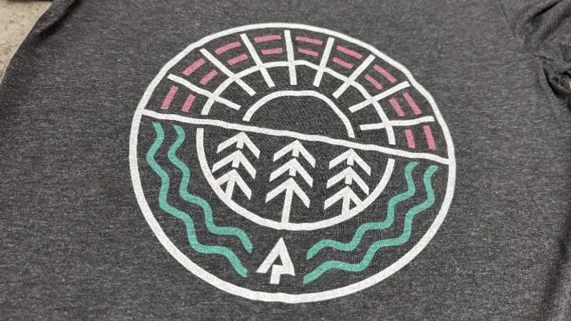 A faded circular emblem discharge-printed onto a grey garment
