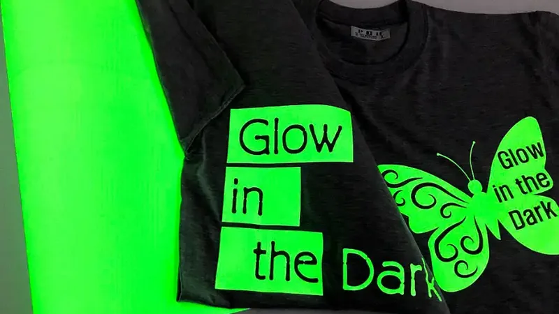 A black tee with a bright green glow-in-the-dark print beside a green butterfly graphic