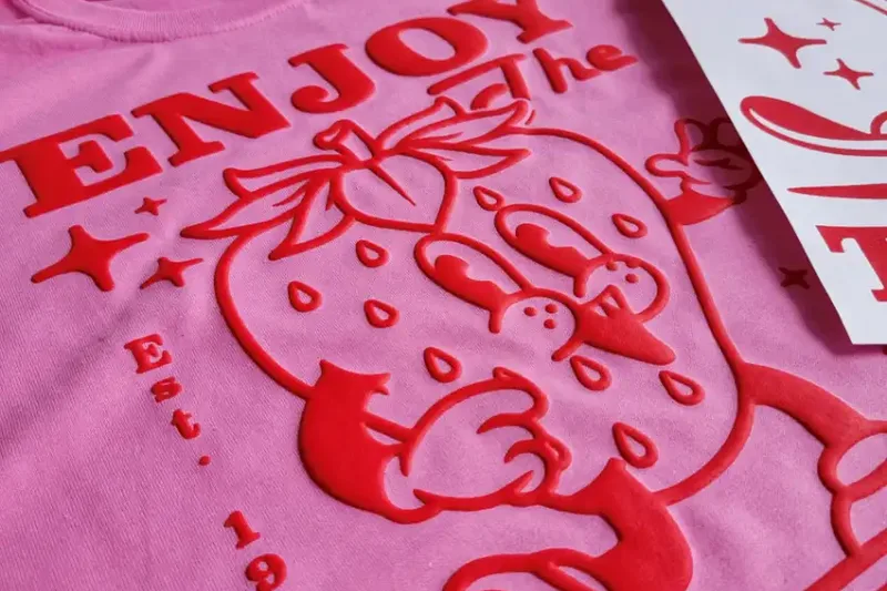 A pink tee with a raised red puff-printed graphic