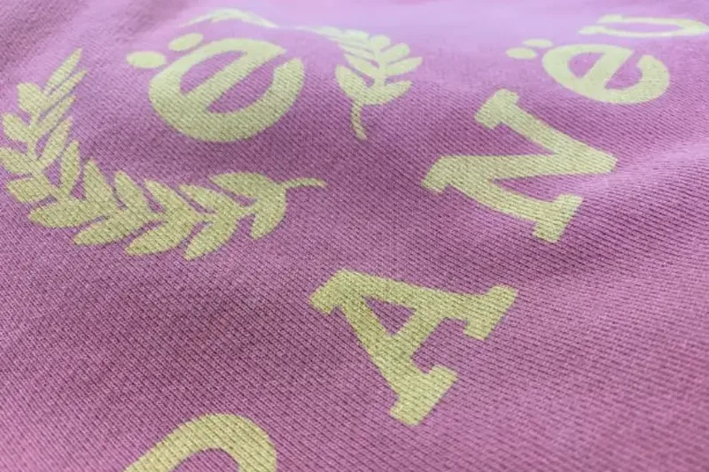Close-up of a soft, pale water-based print on a lilac garment
