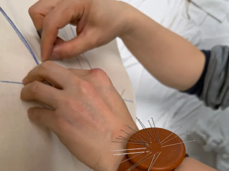 Pattern-maker pinning chalk lines onto a toile — the spec stage