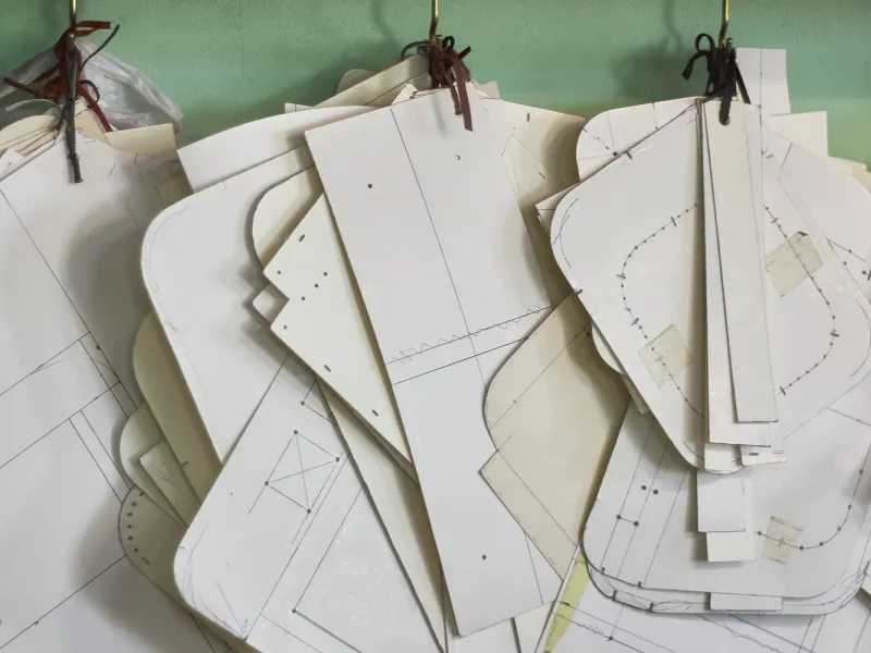 Cardboard pattern pieces hanging from hooks above the cutting table