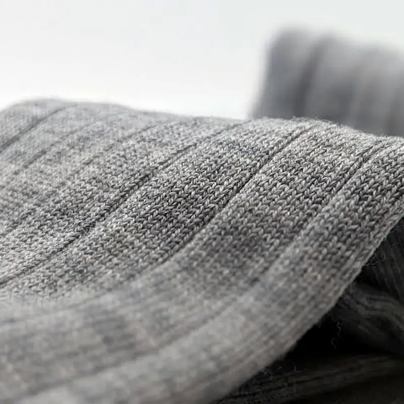 Grey marl rib knitted close, the stitches falling out of focus into a pale ground