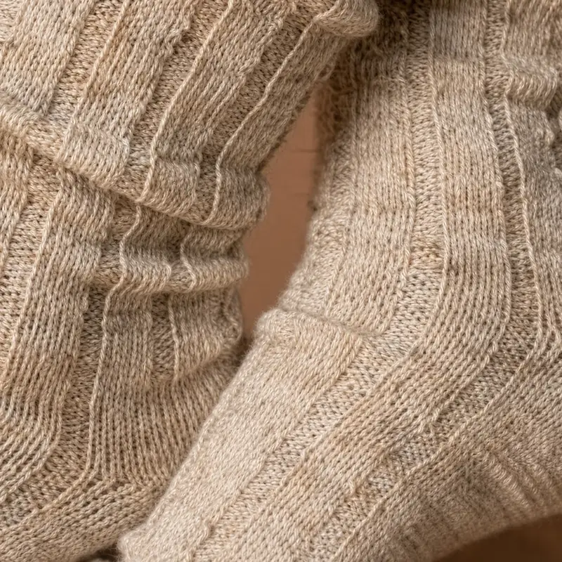 Ribbed knit in undyed natural yarn, its thick vertical lines catching the light