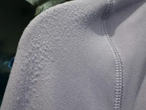 Close-up of stitched shoulder and sleeve seams on a grey performance knit