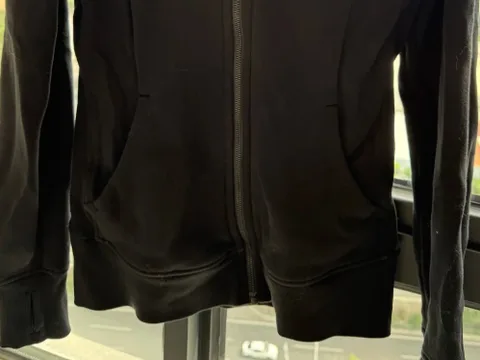 Dark zip-through training jacket on a stand, showing how the fabric drapes