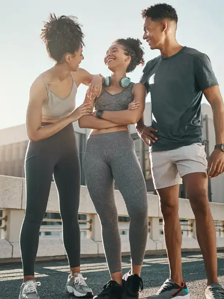 A man and a woman in matching activewear standing against a concrete wall